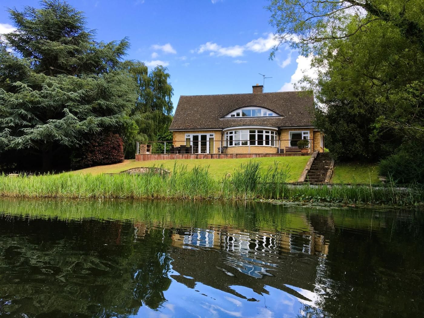 Ein Haus mit Teich, umgeben von Bäumen.
