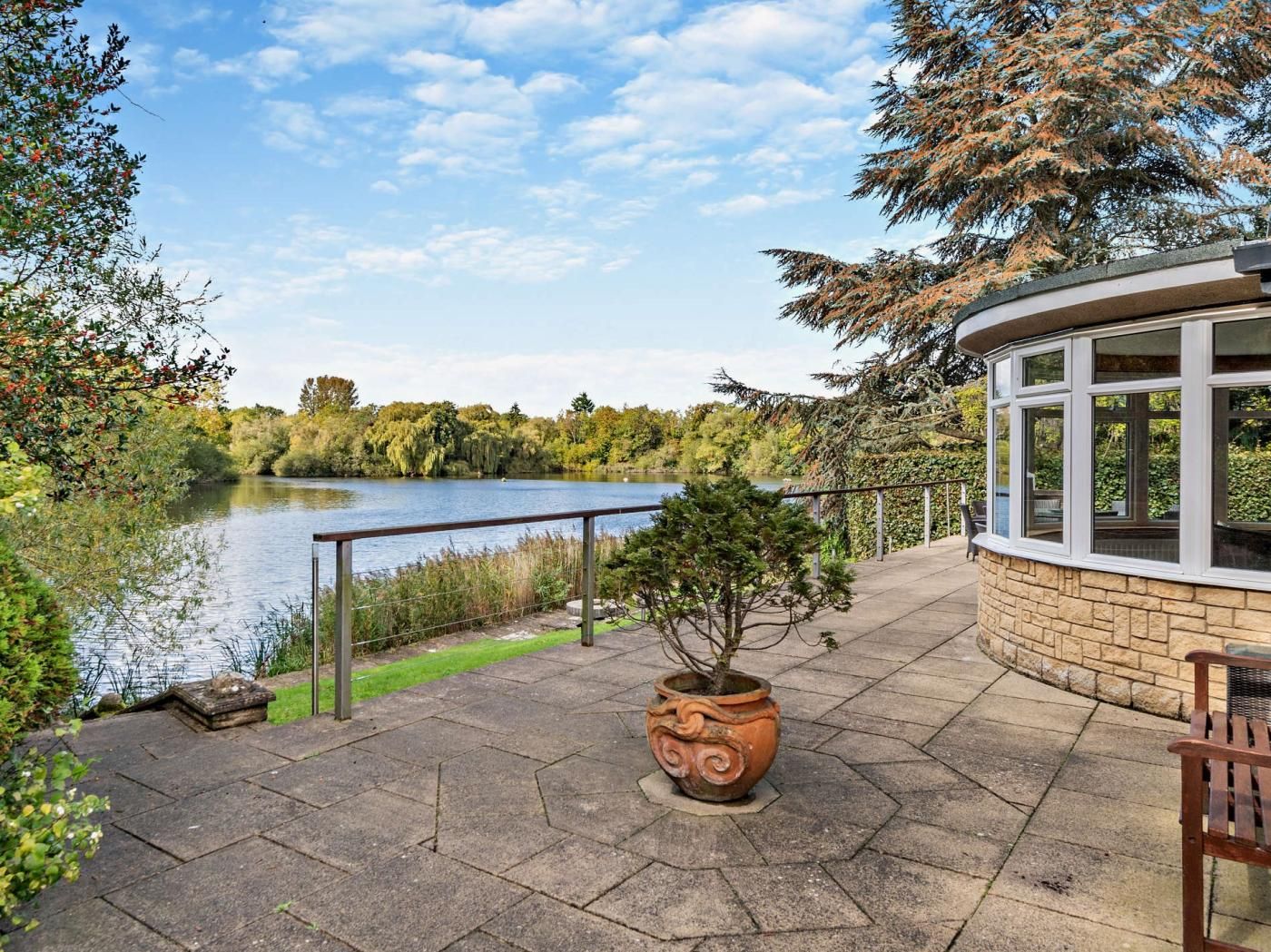 A waterfront patio with a stone pathway, a potted plant, and a seating area with a bench.