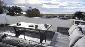 A rooftop patio with a table, chairs, and a view of the beach. - 5 Bed in Aberdovey (oc-93603) (Aberdovey)