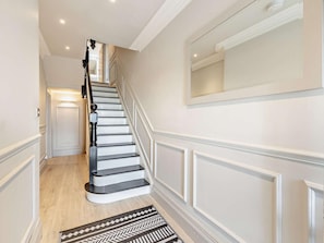 A staircase with white walls and a patterned rug.