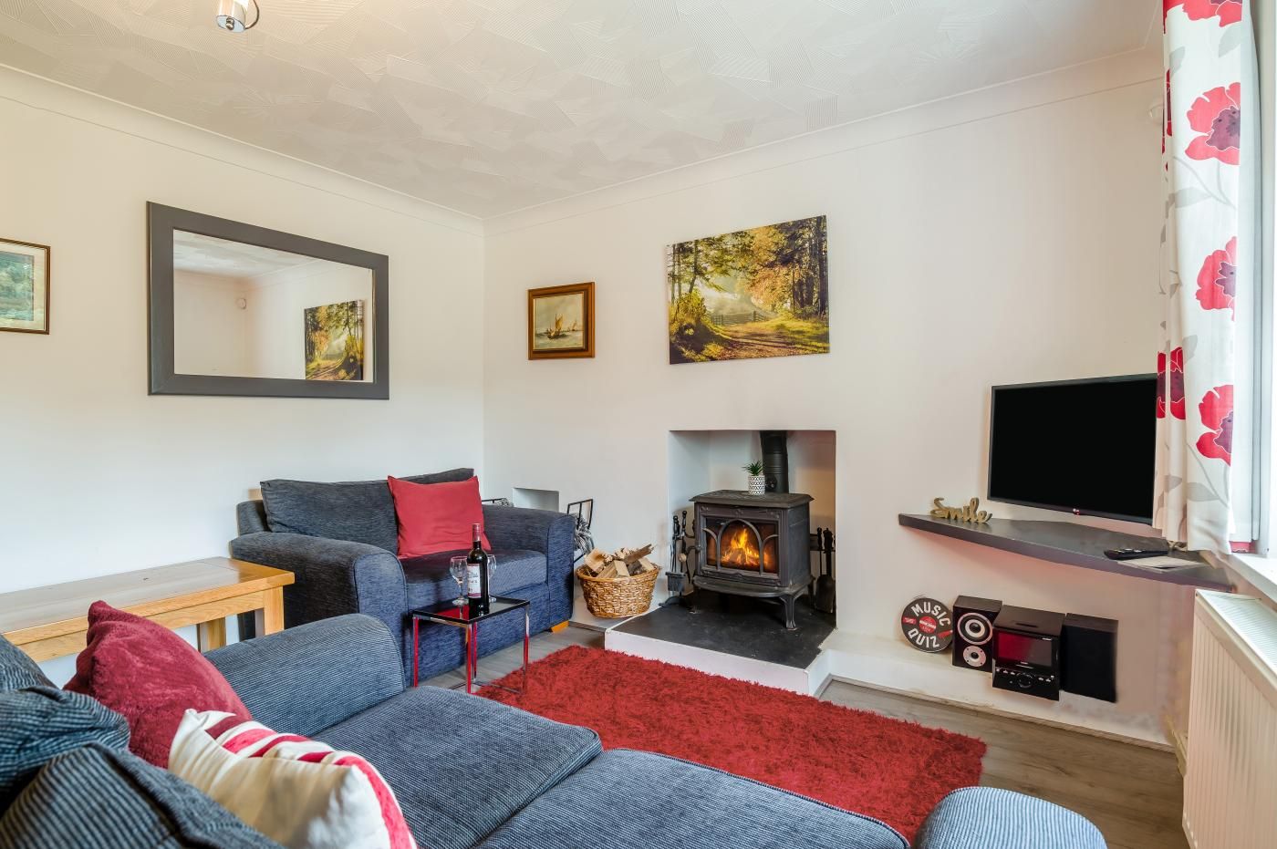 A living room with a sofa, a fireplace, a television, and artwork on the walls.