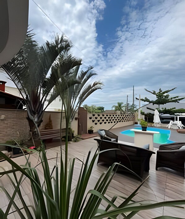 An outdoor patio with a pool, seating area, and potted plants.