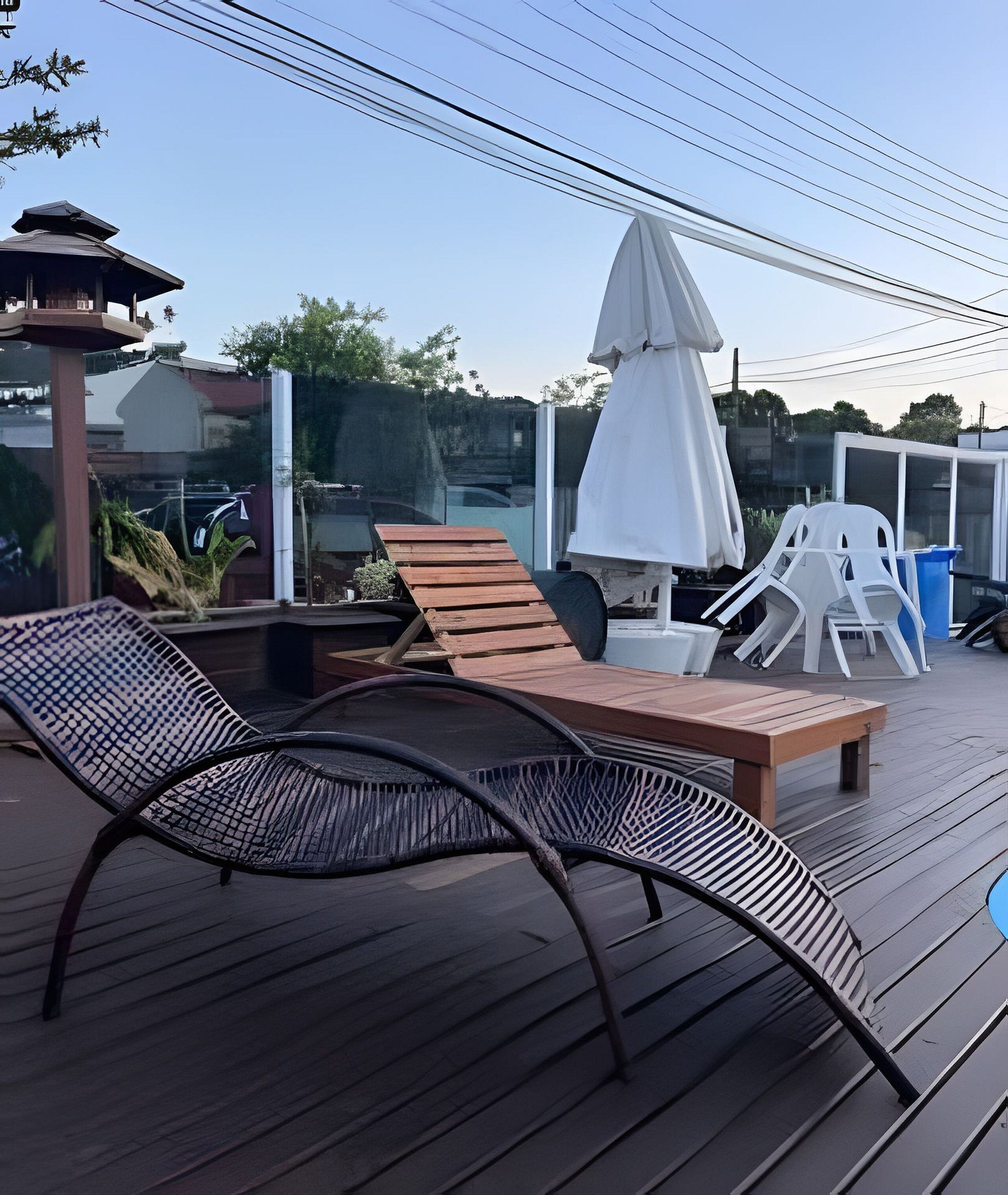 En solterrasse med liggestole, et bord og en parasol.