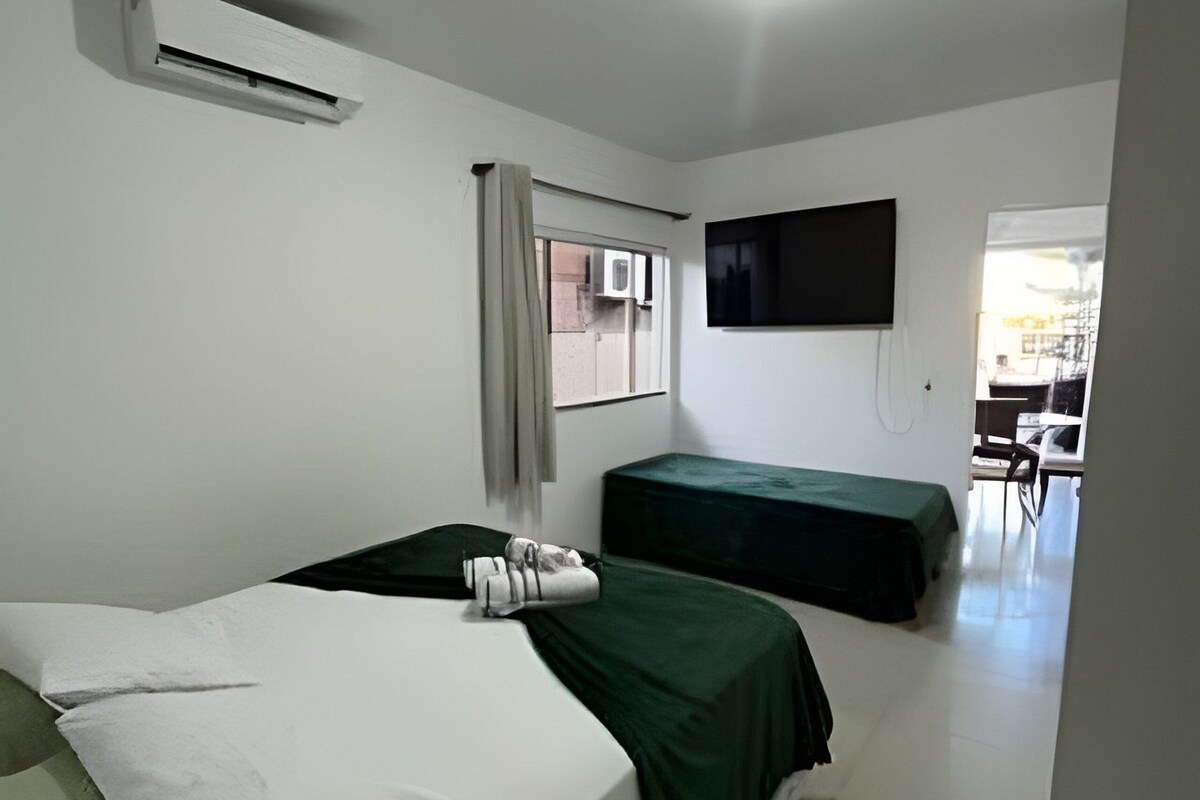 Una habitación con dos camas, un televisor de pantalla plana en la pared y una ventana con cortinas.