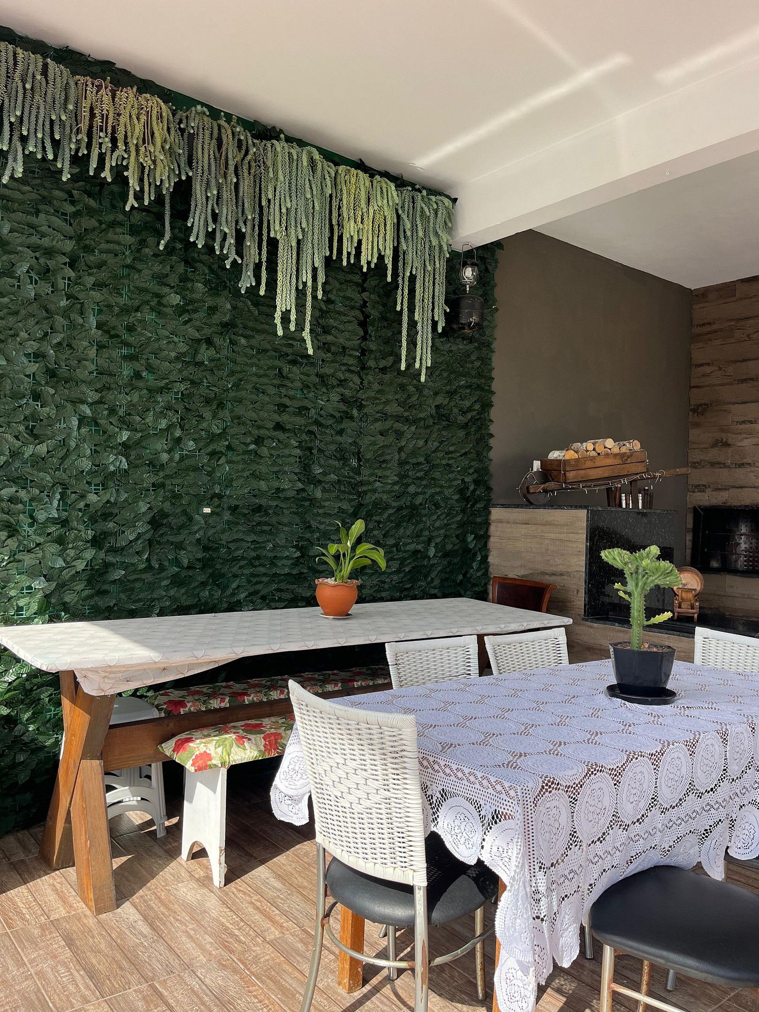 An outdoor dining area with a green wall, white tables, and wicker chairs.