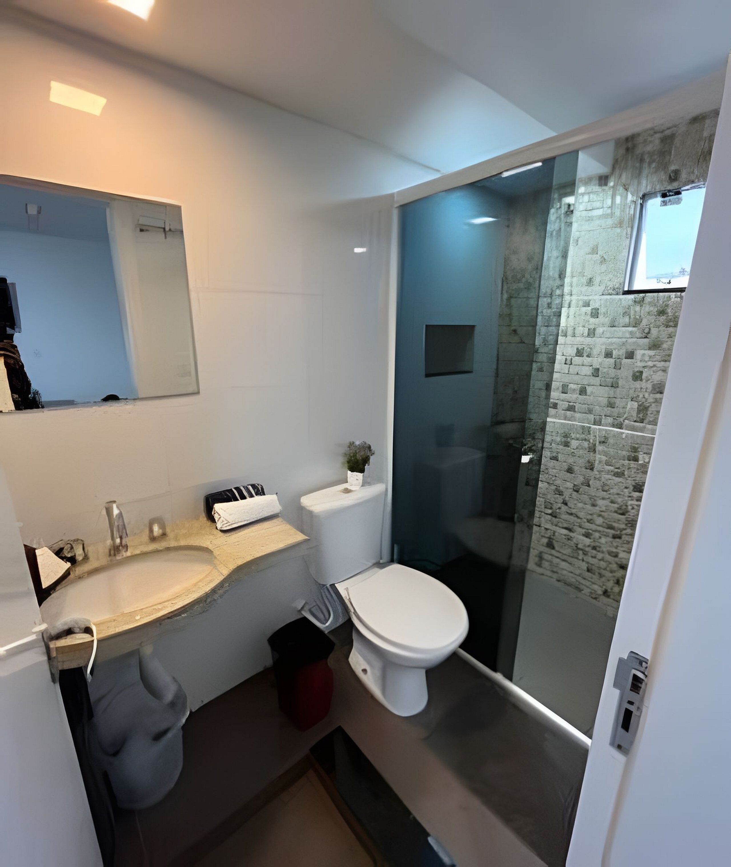 A modern bathroom with a white sink, a toilet, and a glass-enclosed shower area.