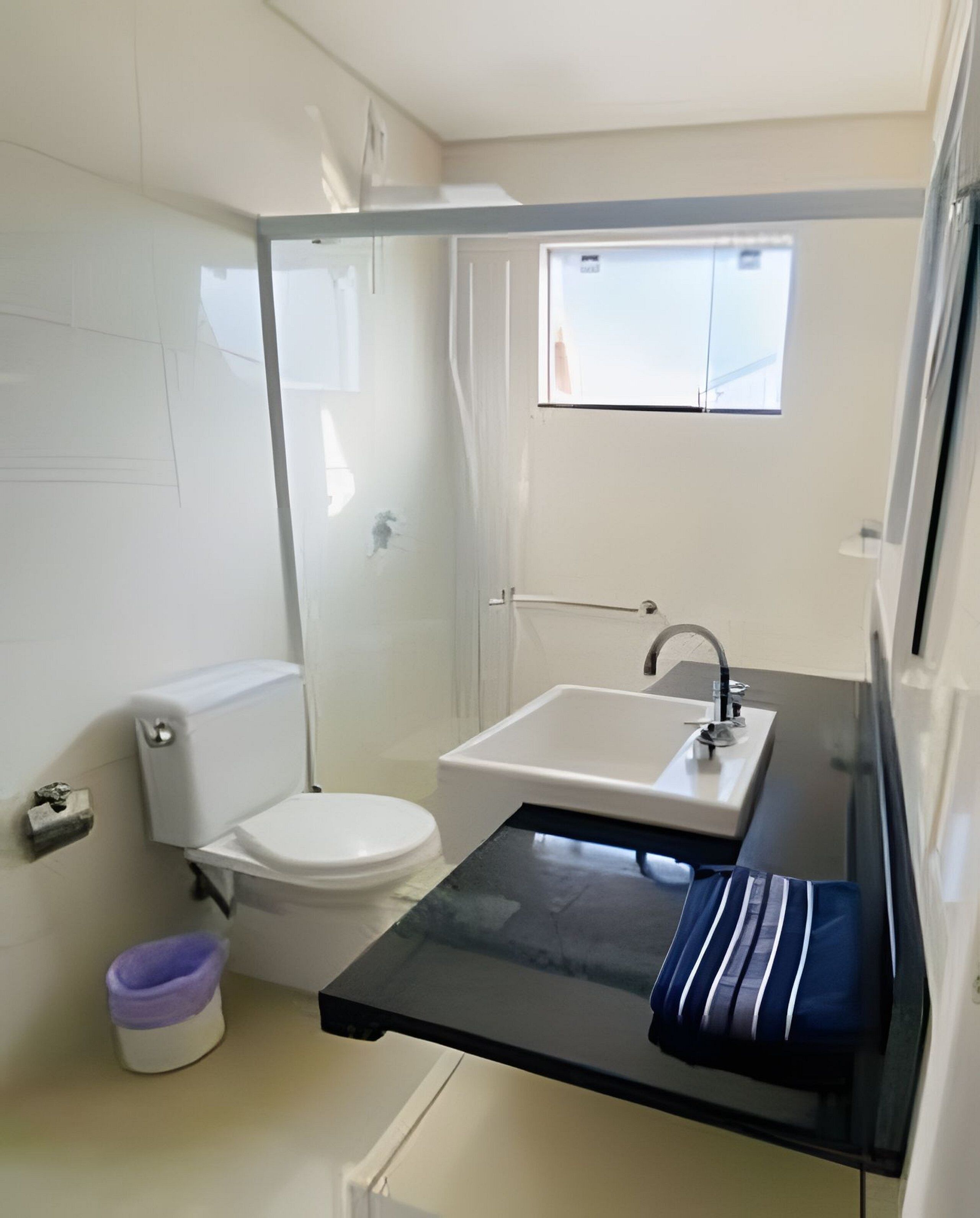 A compact bathroom with a toilet, sink, and shower.