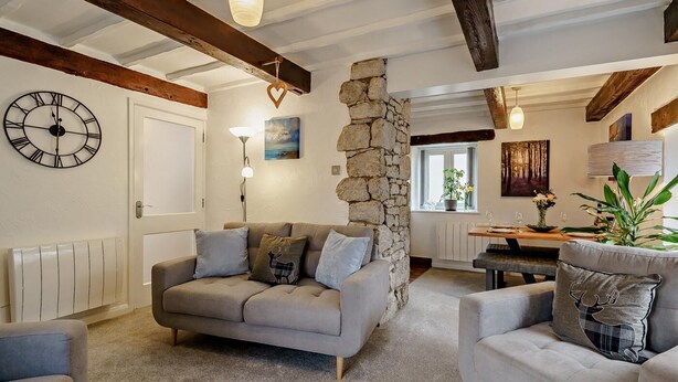 A cozy living room with a stone wall, a sofa, a coffee table, and a dining area with a view. - 2 Bed in Carnforth (oc-90530) (Yealand Redmayne)