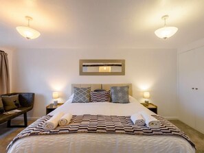 A hotel room with a bed, two bedside tables, a chair, a mirror, and a door. - 3 Bed in Carnforth (oc-90531) (Yealand Redmayne)