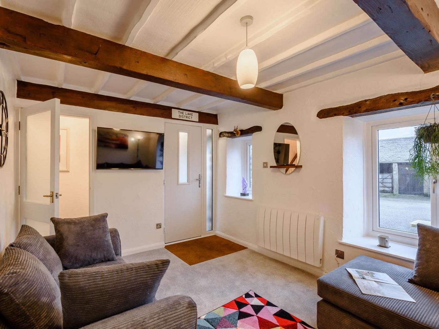 Quarto aconchegante com televisão, espelho e janela com vista para o exterior.