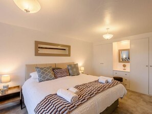 Een hotelkamer met een groot bed, nachtkastjes, een garderobe en een spiegel.