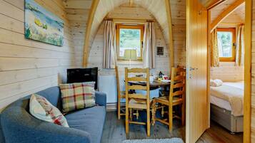 A cozy cabin interior with a dining area, a sofa, and a bed.