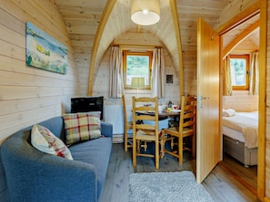 Ein gemütliches Blockhaus-Interieur mit Essbereich, einer Couch und einem Bett.