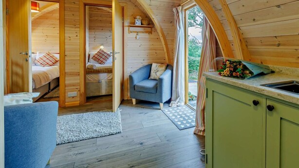 En mysig stuga med ett loft som används som sovrum, ett sällskapsutrymme och ett litet kök.