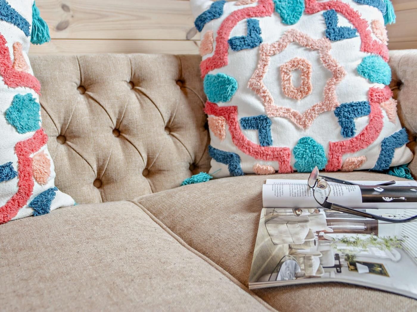 A tufted sofa with a patterned throw pillow and a magazine with a model cityscape.