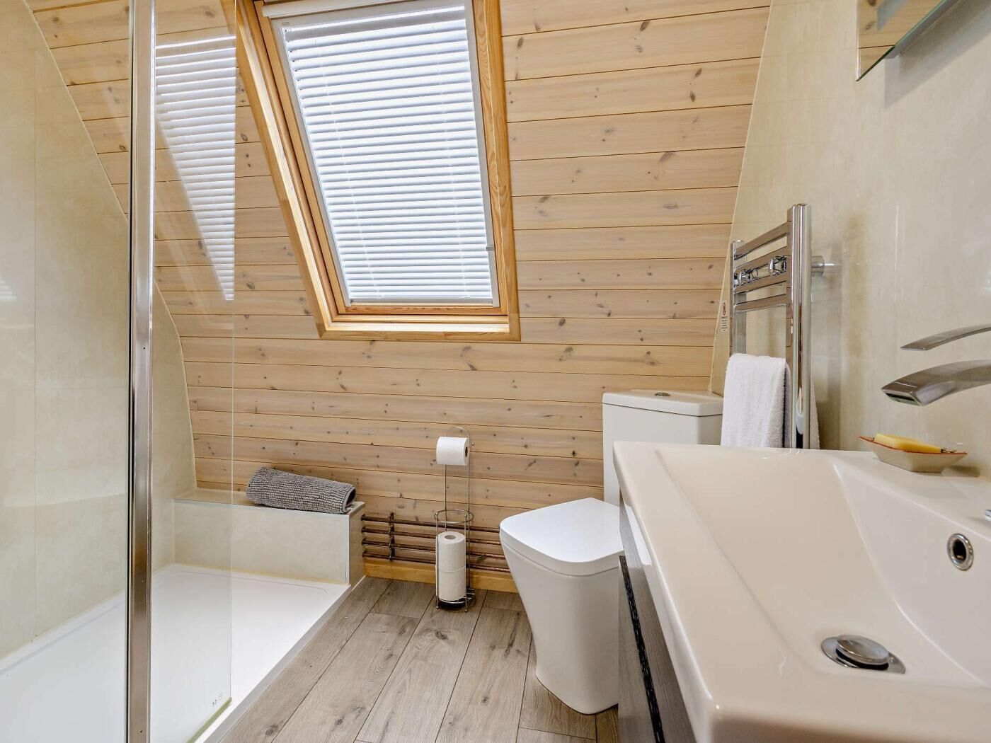 A modern bathroom with a skylight, a bathtub, a toilet, and a shower area.