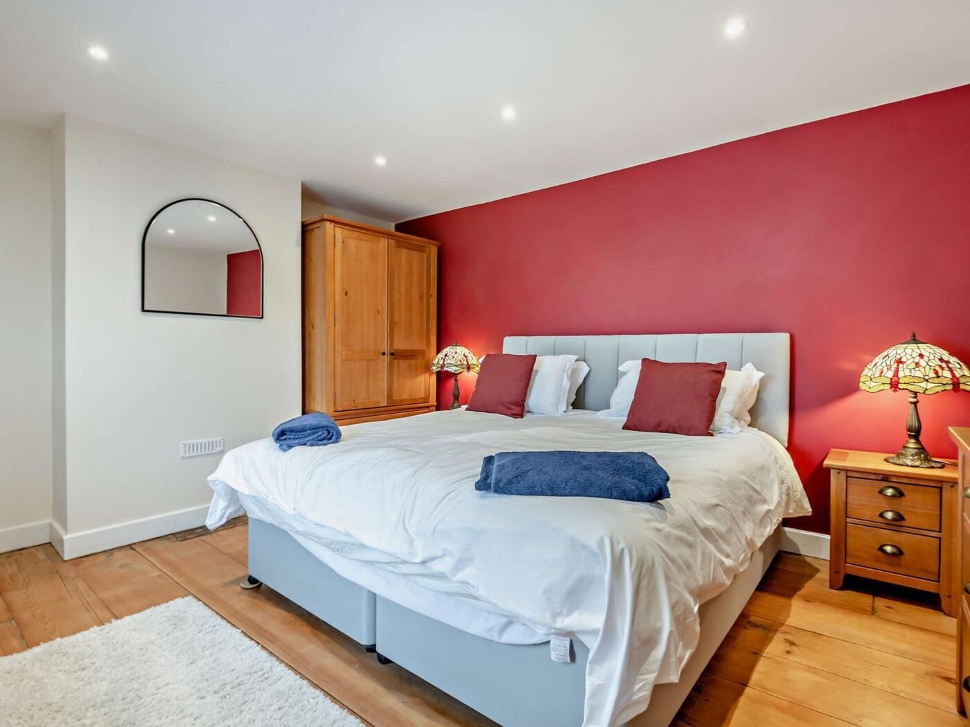 A bedroom with a bed, a wardrobe, a nightstand, and a lamp.