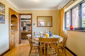 A dining area with a round table, wooden chairs, and breakfast items. - 2 Bed in Dorchester (oc-dc018) (Winfrith Newburgh)