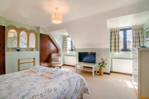 A bedroom with a bed, a chair, a television, and a window with curtains. - 2 Bed in Dorchester (oc-dc018) (Winfrith Newburgh)