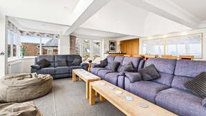 Ein modernes Wohnzimmer mit einer Sofagarnitur, einem Holztisch und Blick ins Freie.