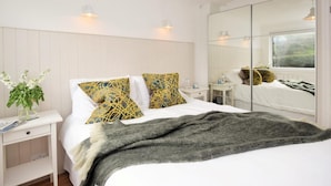 A bedroom with a bed, bedside tables, a mirror, and a window with a view. - 2 Bed in Newquay (oc-43204) (Mawgan Porth)
