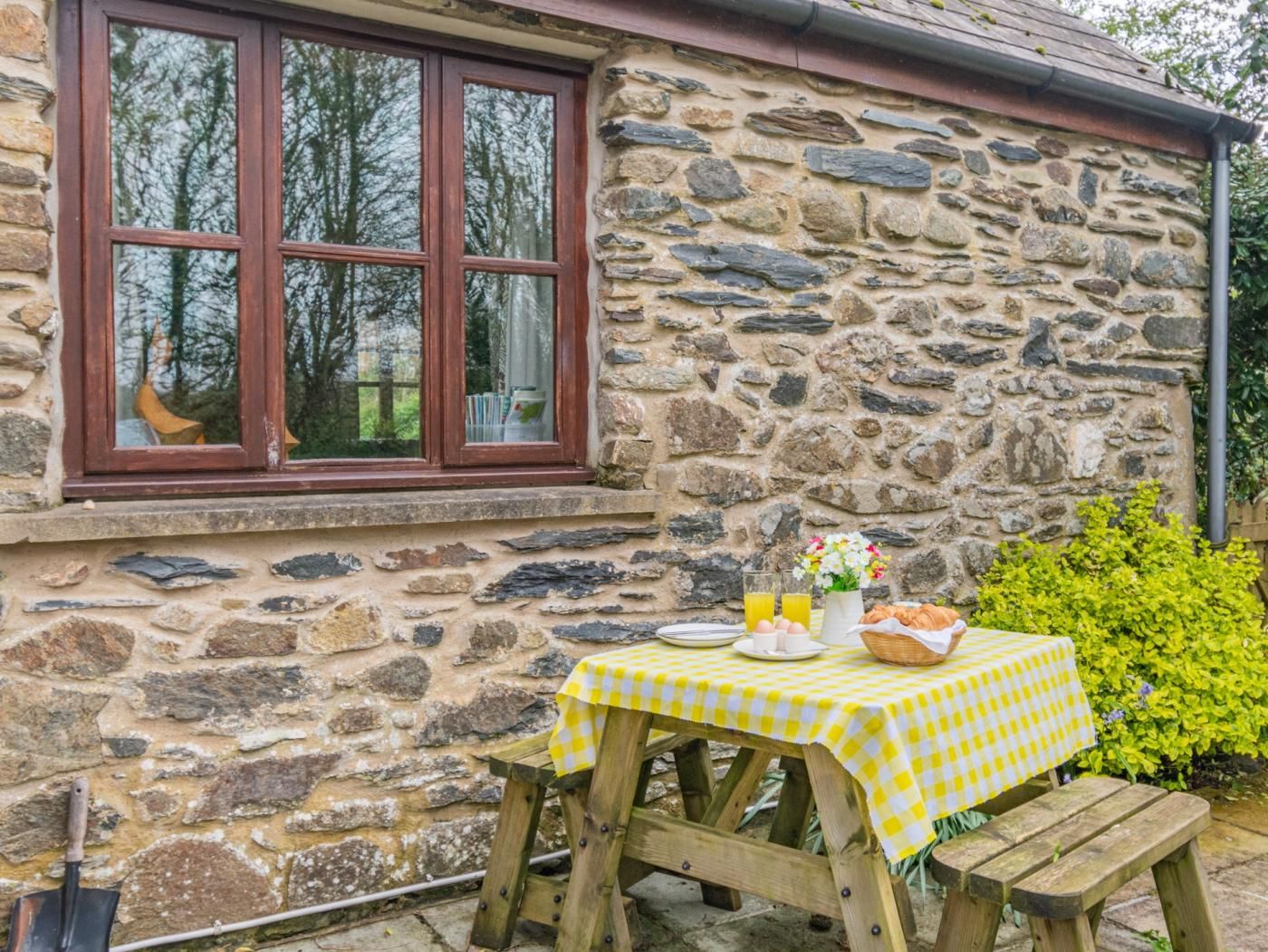Ein Steinhaus mit einem Fenster und einem Tisch, gedeckt mit Frühstück.
