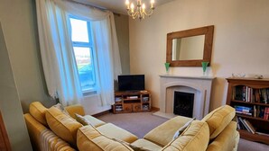 Ein Wohnzimmer mit Sofa, Fernseher, Kamin und Bücherregal.