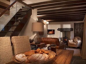 A cozy living room with a fireplace, a sofa, a coffee table with bread, and a staircase. - 1 Bed in Grange Over Sands (oc-lcc32) (Lindale)