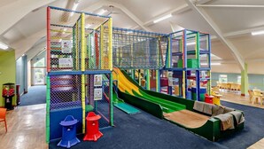 Ein Spielbereich mit Rutsche, Kletternetz und weichen Spielelementen.