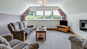 Ein Wohnzimmer mit Sofa, Couchtisch, Fernseher und Kamin.
