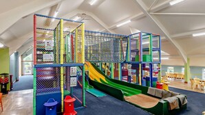 Ein Kinderspielbereich mit Rutsche, Klettergerüsten und bequemen Sitzgelegenheiten.