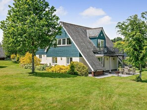 A two-story house with a sloped roof, a balcony, and a well-maintained lawn. - 3 Bed in Crediton (oc-waie4) (Zeal Monachorum)