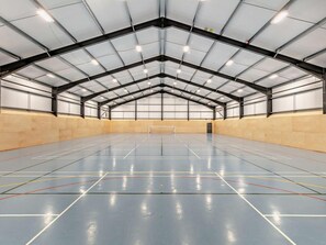 An indoor sports hall with a high ceiling, a tennis court, and a net. - 3 Bed in Crediton (oc-waie4) (Zeal Monachorum)