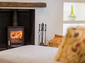 A room with a wood-burning stove, a candle holder, and a woven basket. - 1 Bed in Grange-over-sands (oc-78659) (Cartmel)