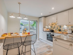 A modern kitchen with a dining area, featuring a large window, a built-in oven, and a tiled backsplash. - 1 Bed in Grange-over-sands (oc-78659) (Cartmel)