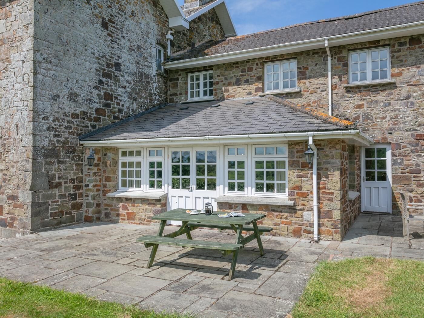 Un bâtiment en pierre doté d’un patio couvert et d’une table de pique-nique.
