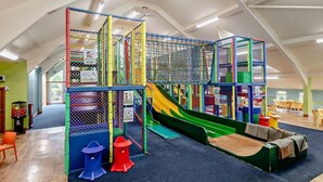 Un área de juegos infantiles con un tobogán, estructuras para escalar y asientos acolchados.