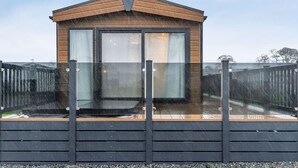 Eine kleine Holzhütte mit Glastür und -fenstern, umzäunt.