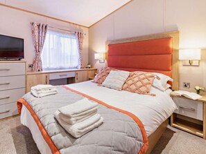 Ein Hotelzimmer mit einem Bett, Nachttischen, einem Fernseher und einem Fenster mit Vorhängen.