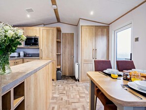Eine moderne Küche mit Holzausstattung, einer Mikrowelle und einem Essbereich mit Frühstückstisch.