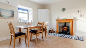 Un coin repas avec une table et des chaises en bois, une cheminée et une horloge au mur.