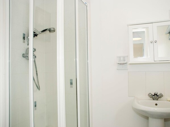 Une salle de bain avec une douche à parois de verre, un lavabo blanc et un meuble au-dessus du lavabo.