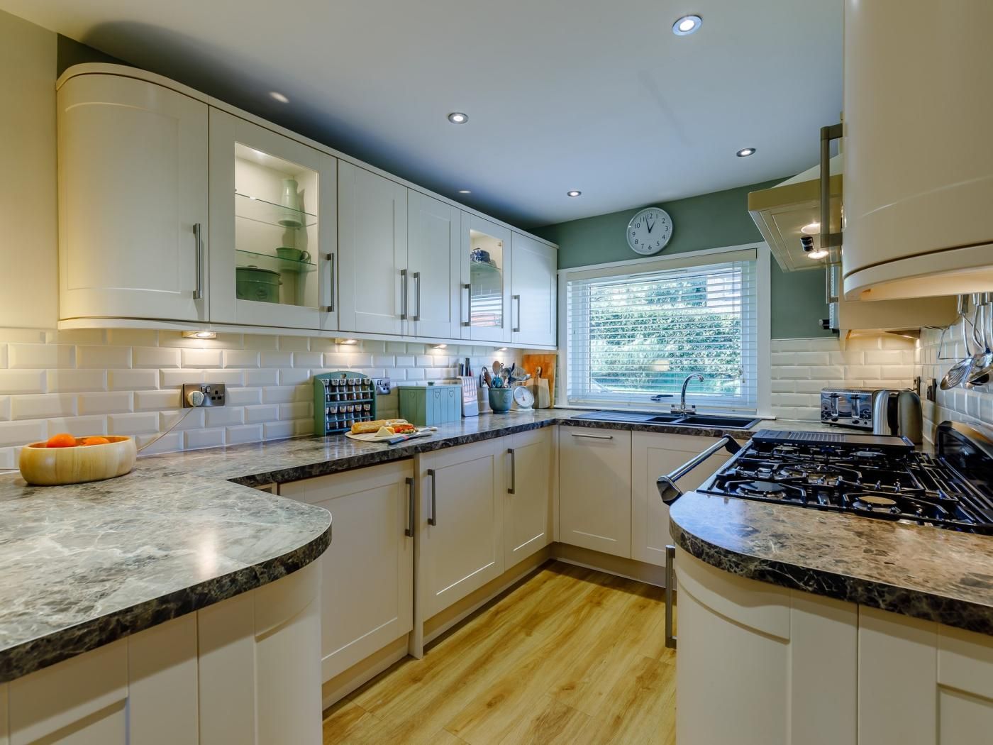 A modern kitchen with white cabinets, a marble countertop, and a built-in stove.