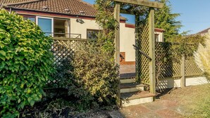 Ein Wohnhaus mit Holztor, befestigtem Zugangsweg und einem Dach mit Ziegeldeckung.