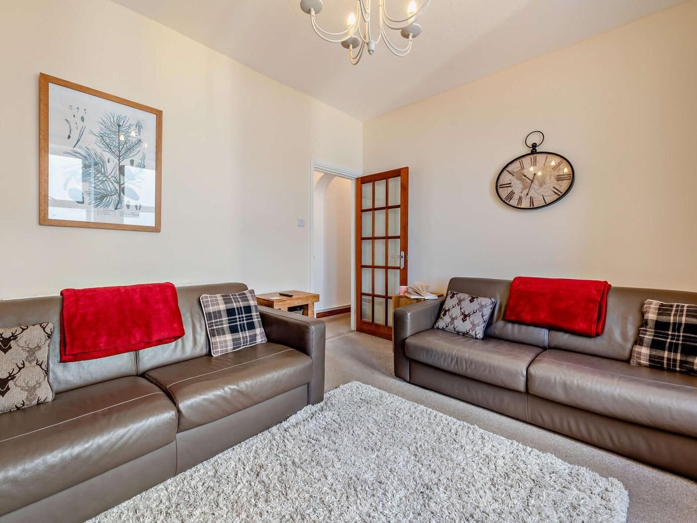 Ein Wohnzimmer mit zwei Ledersofas, einem Teppich, einer Uhr und einem gerahmten Bild an der Wand.