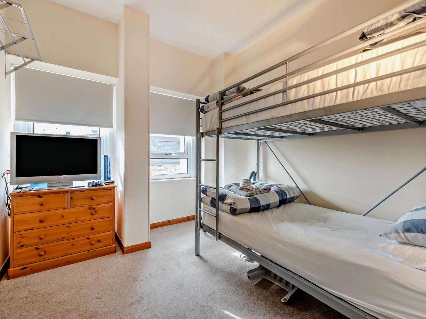 A compact room with bunk beds, a television, and a wooden dresser.