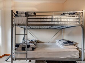 Ein Etagenbett mit zwei Schlafstellen, einer Stehleiter und einem Staubsauger auf dem Boden.