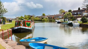A canal with a narrowboat docked at a lock, surrounded by houses and small boats. - 2 Bed in Honiton (oc-93402) (Luppitt)