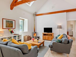 Ein modernes Wohnzimmer mit Kamin, grauen Sofas, einem Holztisch und einem Fernseher.