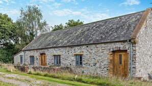 A stone building with a gravel path leading to it, wooden doors, and windows. - 2 Bed in Honiton (oc-93402) (Luppitt)